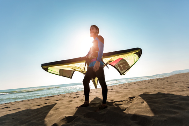 彼の凧の砂浜に立っているハンサムな白人男プロ サーファー - 写真・画像