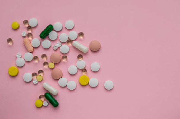 píldoras multicolores dispersas sobre un fondo rosa
 - Foto, Imagen