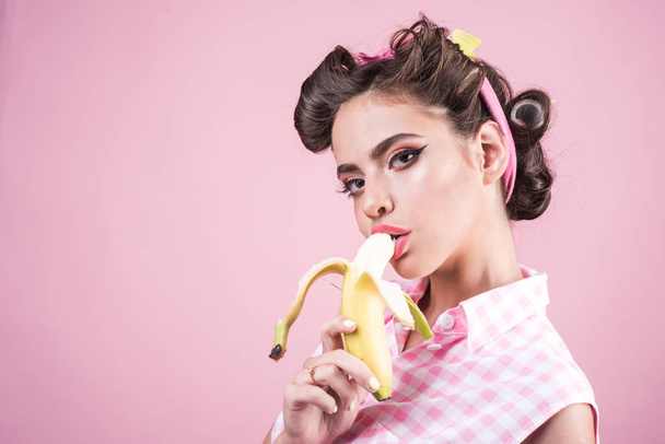 banana dieting. pin up woman with trendy makeup. pinup girl with fashion hair. retro woman eating banana. pretty girl in vintage style, copy space. Selling health - Foto, afbeelding