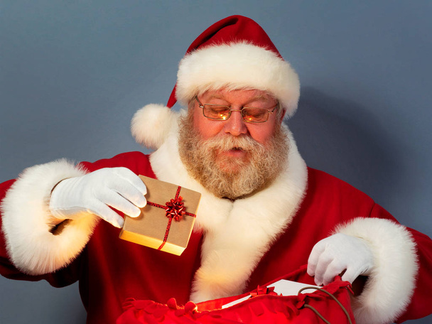 Santa Claus putting gifts into his sack - Фото, зображення