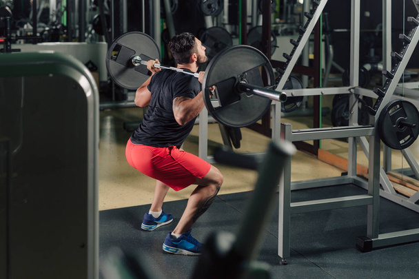 Homme fort dans la salle de gym faisant squats
 - Photo, image
