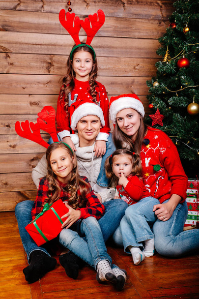 Grande famille souriante dans des chapeaux de Père Noël avec de nombreuses boîtes-cadeaux assis près de l'arbre de Noël à la maison. Joyeux Noël et Joyeuses Fêtes
 - Photo, image