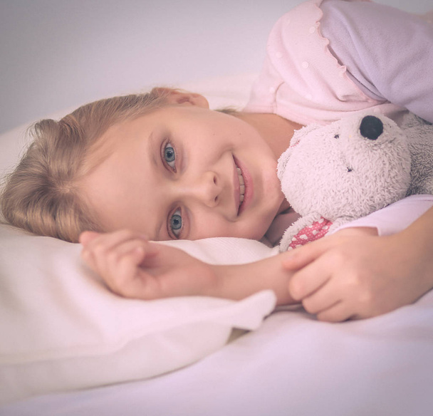 Child little girl sleeps in the bed with a toy teddy bear. - Fotografie, Obrázek