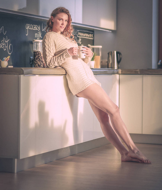 Young woman standing in kitchen. - Φωτογραφία, εικόνα