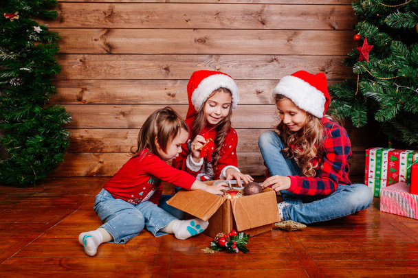 Merry Christmas and Happy Holidays. Cute little sisters decorate the tree at home. - Foto, imagen