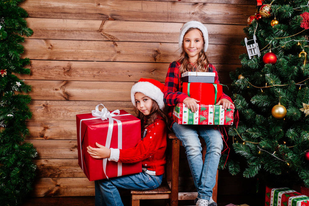 Merry Christmas and Happy Holiday. Two cute little child girls with present gift boxes near tree at home. - Foto, imagen