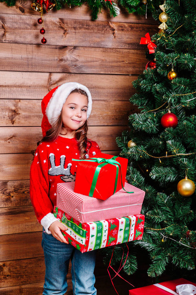 Cute little child girl with present gift boxes near tree at home. - Φωτογραφία, εικόνα