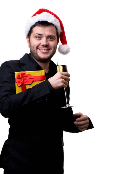 Picture of man in Santa hat with gift and glass of champagne in hands - Zdjęcie, obraz