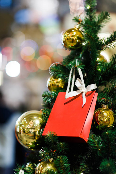 Bild der Weihnachtstanne mit Goldkugeln, rotes Päckchen für Geschenke . - Foto, Bild