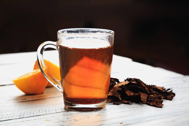 Чашка гарячого чаю, сушене листя чаю та лимонні клини
 - Фото, зображення