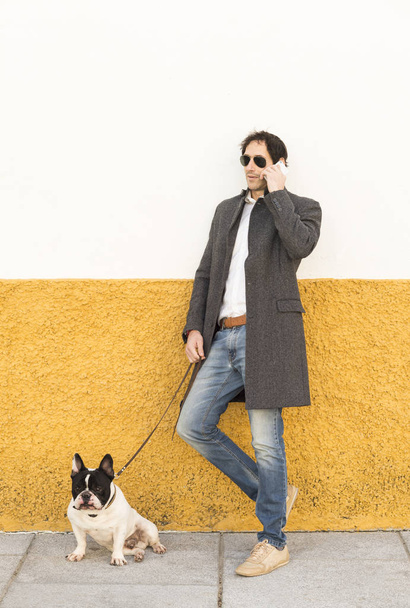 Urban scene of a man with a french bulldog talking by phone - Photo, Image
