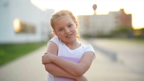 Nahaufnahme Porträt eines blonden europäischen kleinen Mädchens, das mit allen Zähnen lächelt. Ein fröhliches Kind an einem sonnigen Nachmittag sorgt dafür, dass sich alle Eltern wohlfühlen. Kindliches Lächeln ist eine Quelle positiver Emotionen. - Filmmaterial, Video