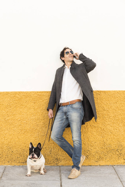 Urban scene of a man with a french bulldog talking by phone - Foto, afbeelding