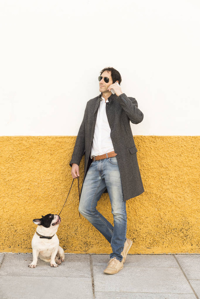 Urban scene of a man with a french bulldog talking by phone - 写真・画像