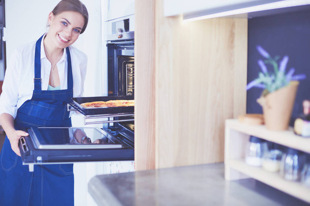 Happy young woman cooking pizza at home - Foto, Bild