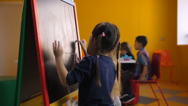 Vidám multi etnikai lányok támaszkodva chalkboard - Felvétel, videó