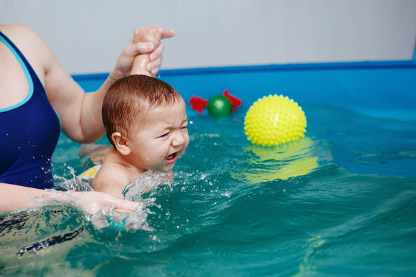 Madre con ejercicios de bebé en la piscina. Estilo de vida saludable, rehabilitación de agua, acuaterapia
. - Foto, imagen