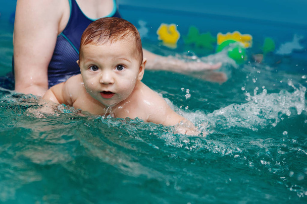 Mother with baby exercises in the pool. Healthy lifestyle, water rehabilitation, aquatherapy. - Fotoğraf, Görsel