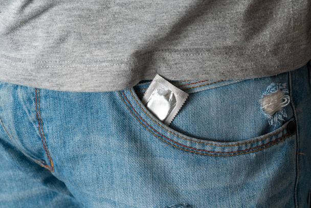 Kondom in der Tasche einer blauen Männer-Jeans mit Reißverschluss. Konzept von Sex, Verführung, Erotik, Schutz, Safe Sex - Foto, Bild