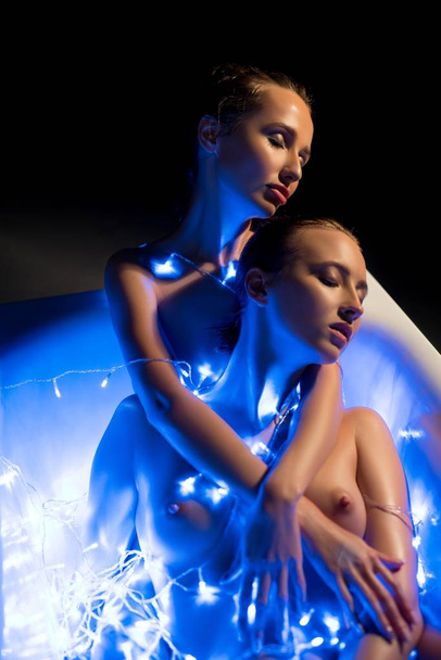 Γυμνές γυναίκες στο λουτρό στα φώτα γιρλάντα στο σκοτάδι - Φωτογραφία, εικόνα