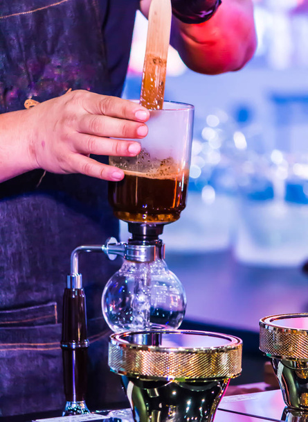 Syphon Coffee o Vacuum Coffee es una inmersión completa de buen gusto, esta imagen muestra mezclar granos de café en agua hirviendo y remover 10 veces
. - Foto, Imagen