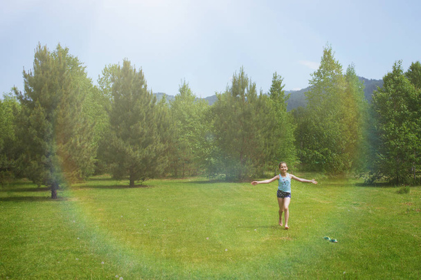 Teen dziewczyna w szorty i niebieski T-shirt na polanie z zielonej trawy i drzew. - Zdjęcie, obraz