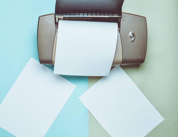 A printer with blank paper forms on a colored pastel background. Top view, flat lay. - Photo, Image