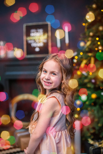 Little girl under the Christmas tree. A girl with gifts under the tree in anticipation of magic, a gift from Santa Claus - Фото, изображение