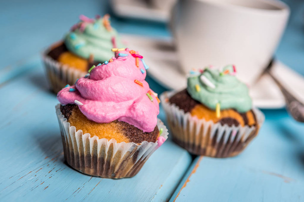 色ピンク グリーン ブルー テーブルにクリームとチョコレートのカップケーキ - 写真・画像