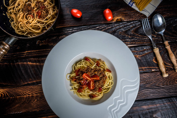 伝統的なイタリアン パスタのミートソースひき肉とダークウッドのテーブル トップ ビューにトマト - 写真・画像
