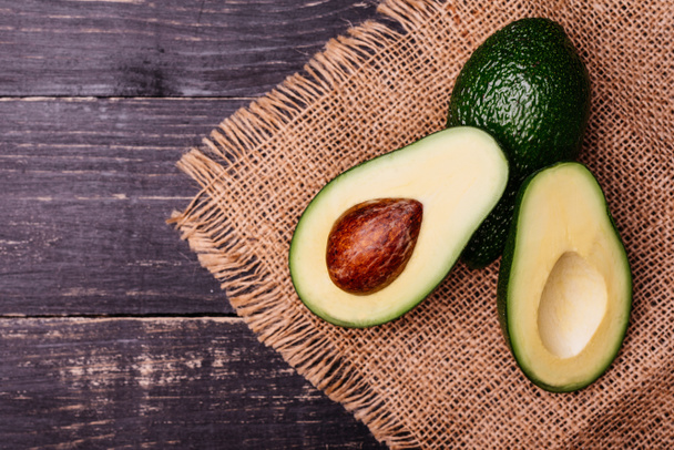 Voedsel, avocado, gezond eten. Snijden door avocado tegen een donkere achtergrond. Het kan worden gebruikt als achtergrond - Foto, afbeelding
