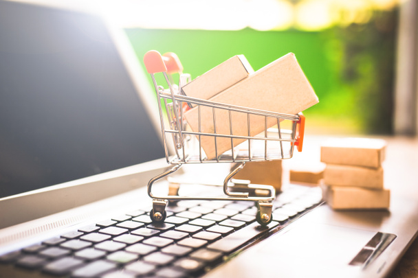 Boxes in a shopping cart over laptop keyboard.Concept about shopping and online sales. Buy your goods directly from the Internet, from the comfort of your home. - Fotó, kép