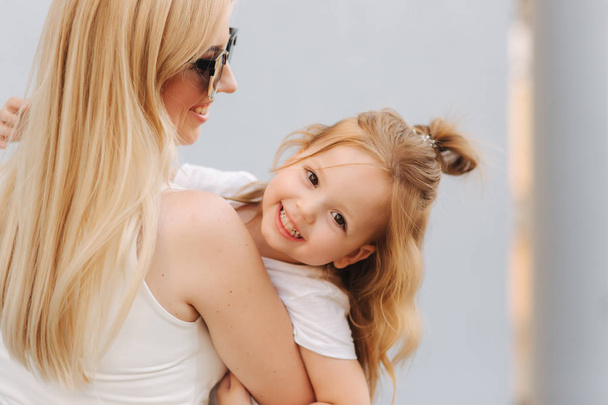 Beautiful mothe with her daughter. Blond hair female. Gray background. Best friends - Φωτογραφία, εικόνα