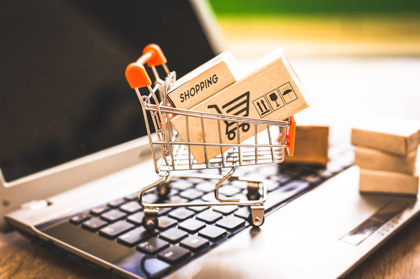 Vakken in een winkelwagentje over laptop toetsenbord. Begrip over winkelen en online verkoop. Uw goederen kopen rechtstreeks van het Internet, vanuit het comfort van uw huis. - Foto, afbeelding