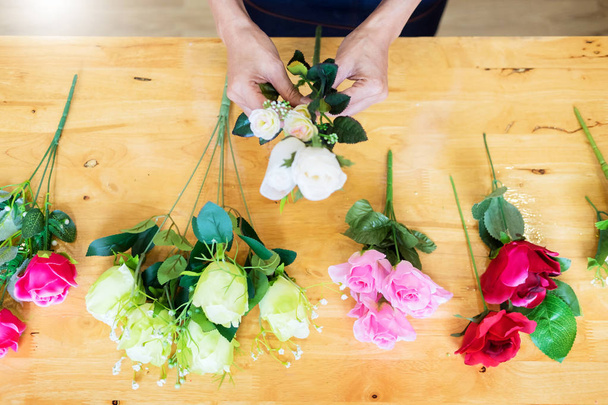 Ženské květinářství v práci pomocí zajištění tvorby krásné umělé kytice vesta v květinářství, obchod, prodej a floristika řemesel a ruka se koncept - Fotografie, Obrázek