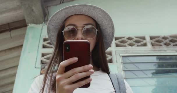Tyylikäs nainen älypuhelimella lähellä nuhjuinen rakennus
 - Materiaali, video
