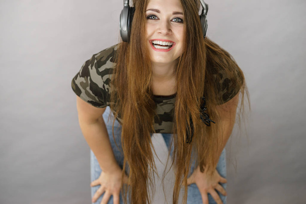Cheerful teenage woman listening to music through big headphones having fun. Crazy girl - Φωτογραφία, εικόνα