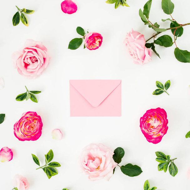 Florale Komposition aus rosa Rosen und rosa Umschlag auf weißem Hintergrund. flache Lage, Draufsicht. Valentinstag - Foto, Bild