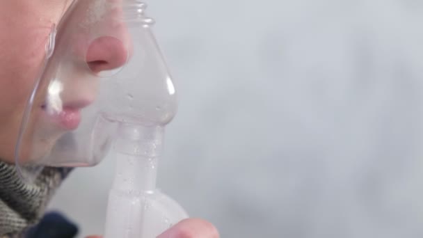 Sick boy inhaling through inhaler mask, nose and lips close-up side view. Use nebulizer and inhaler for the treatment. - Video, Çekim