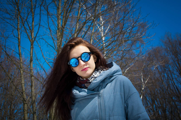 Bahar için bekliyor. Parlak güneşli bir erken baharda güneş gözlüğü parkta güzel şık kız yürüyor - Fotoğraf, Görsel