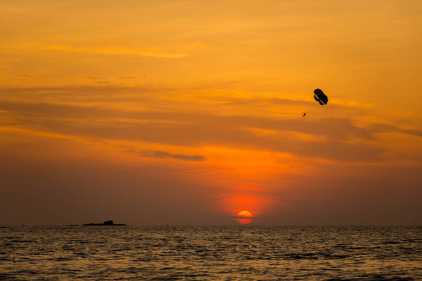 Paraquedas de esportes aquáticos na praia de Pantai Cenang na ilha tropical Langkawi, na Malásia. Bela natureza do sudeste asiático durante o pôr do sol colorido
. - Foto, Imagem