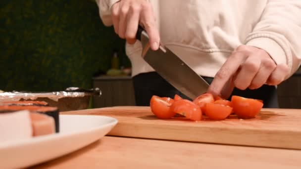 Closeup of girls hands at home kitchen on a wooden cutting board knives small cherry tomatoes with a knife. Home cooking - Filmagem, Vídeo