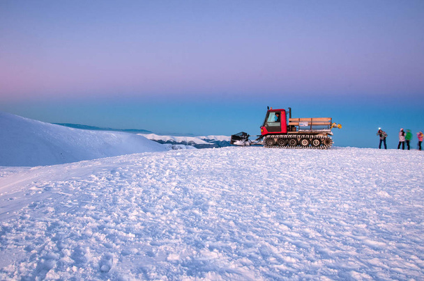 Lumikissa vuorella auringonnousun aikaan talviaamuna. Ratrak on yhtä kuin lumi laskettelurinteellä hiihtokeskuksessa Karpaateilla.
. - Valokuva, kuva