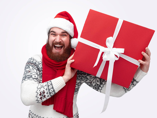 smiling man with a beard holding red christmas box - Foto, Imagem