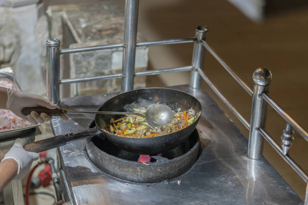 Profesyonel şef ve ateş. Bir açık ateş üzerinde pişirme sebze ve gıda. Profesyonel şef aşçılar stil Flambe. O açık alevler ile bir tavada yemek hazırlar - Fotoğraf, Görsel