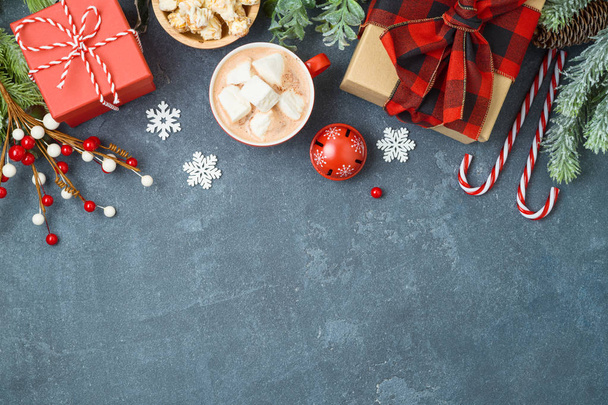 Christmas holiday background with gift boxes and hot chocolate cup on blackboard. Top view from above - 写真・画像