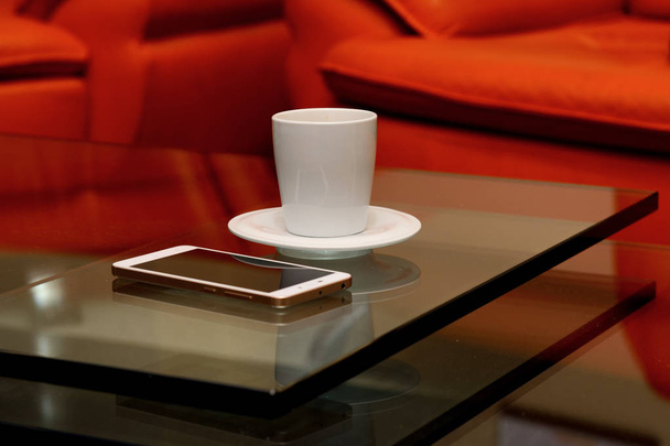 cam üzerine bir fincan kahve ve bir beyaz smartphone tablodur - Fotoğraf, Görsel