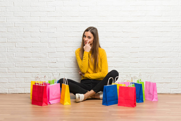 Chica joven con un montón de bolsas de compras mirando hacia el frente
 - Foto, imagen