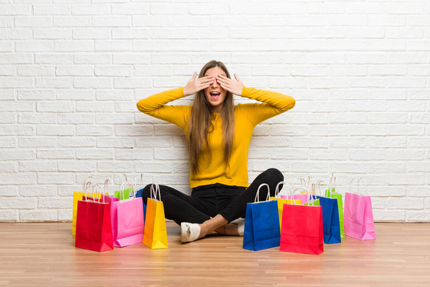 Chica joven con un montón de bolsas de compras que cubren los ojos por las manos. Sorprendido de ver lo que está por venir
 - Foto, imagen