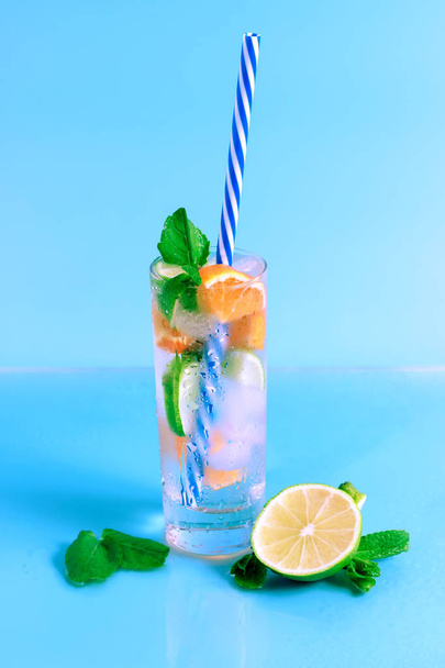 Fresh cocktail with lime, orange and ice on blue background. Summer background. - Zdjęcie, obraz